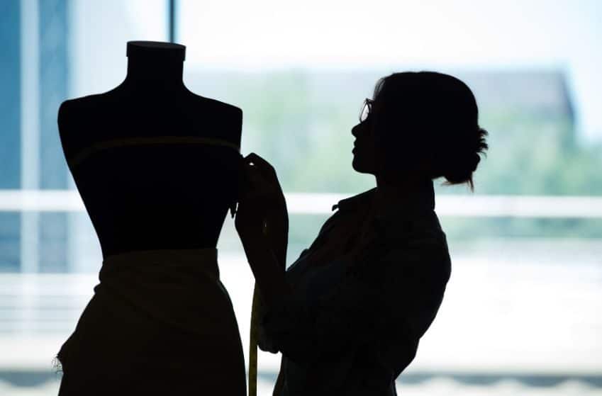 Couturière prenant des mesures sur mannequin dans un atelier couture sur-mesure