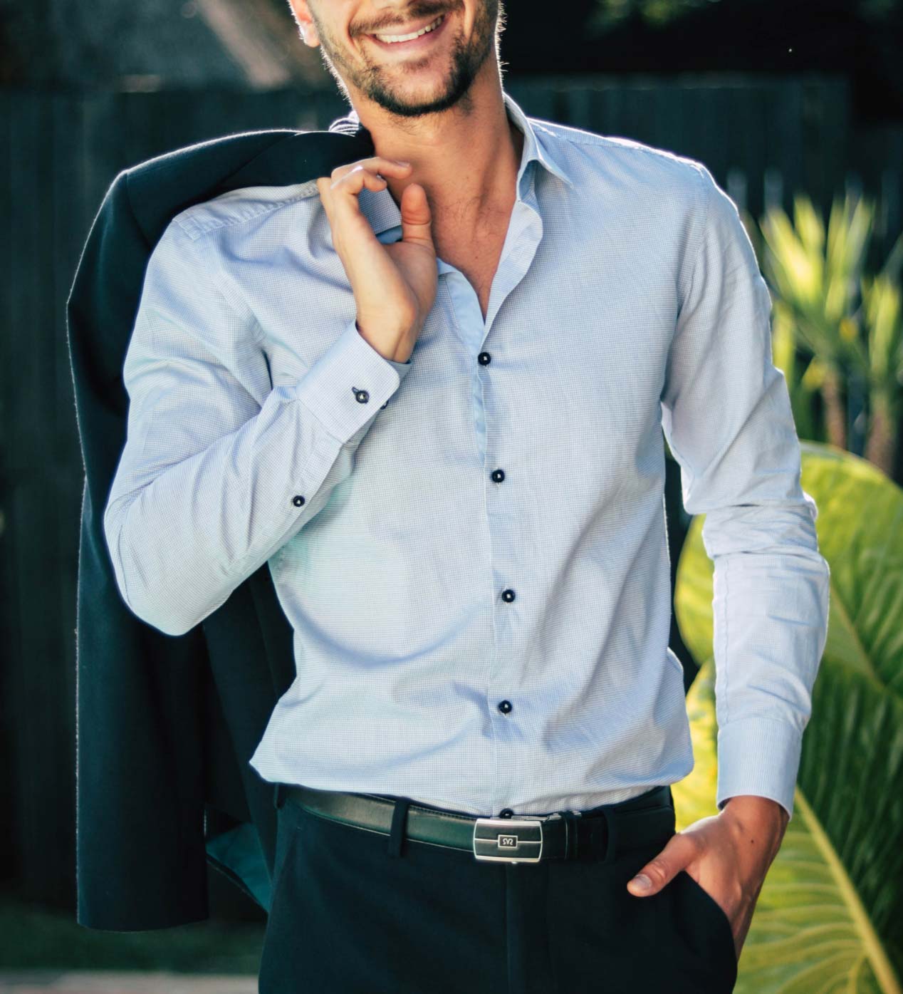 Homme portant une chemise bleu clair ouverte avec une veste sur l’épaule