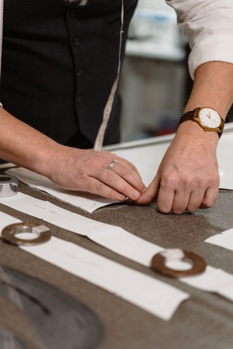 Mains ajustant des patrons sur un tissu dans un atelier de couture sur-mesure