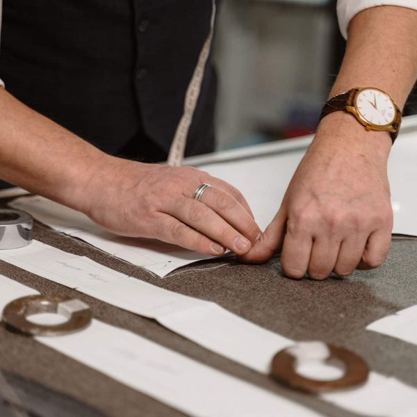 Mains ajustant des patrons sur un tissu dans un atelier de couture sur-mesure