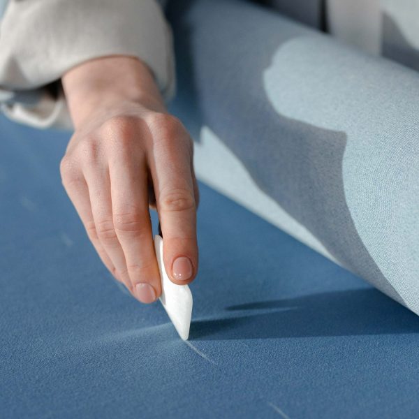 Main traçant des repères sur un tissu dans un atelier de couture sur-mesure