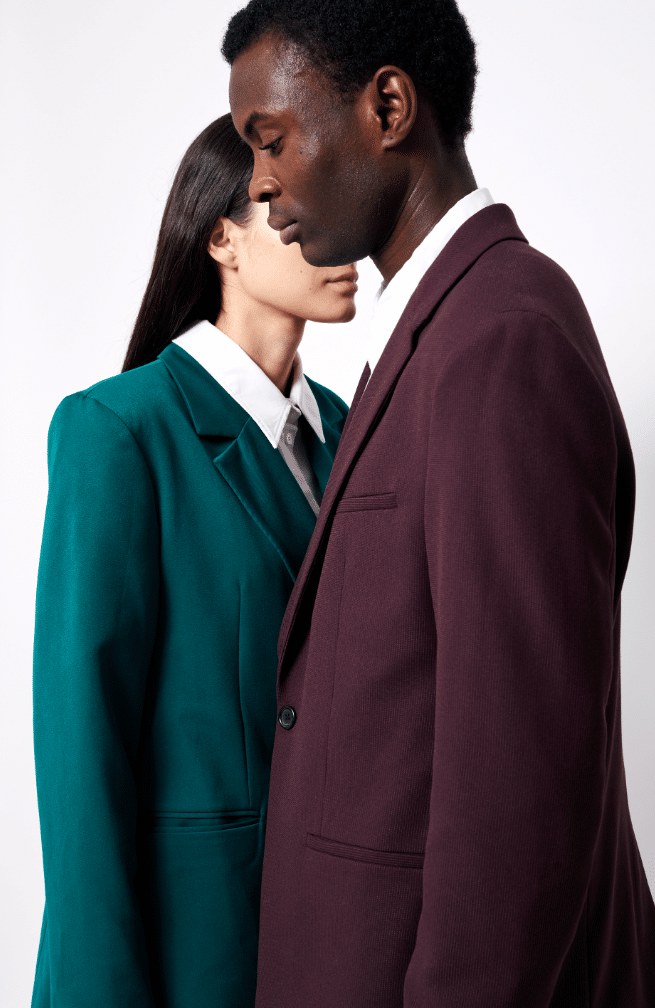 Homme en costume bordeaux et femme en blazer vert posant ensemble